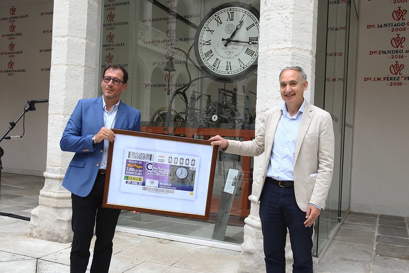 El rector de la Universidad de Valladolid, Antonio Largo Cabrerizo, y el delegado territorial de la ONCE en Castilla y León, Ismael Pérez Blanco, con la lámina enmarcada con el cupón.